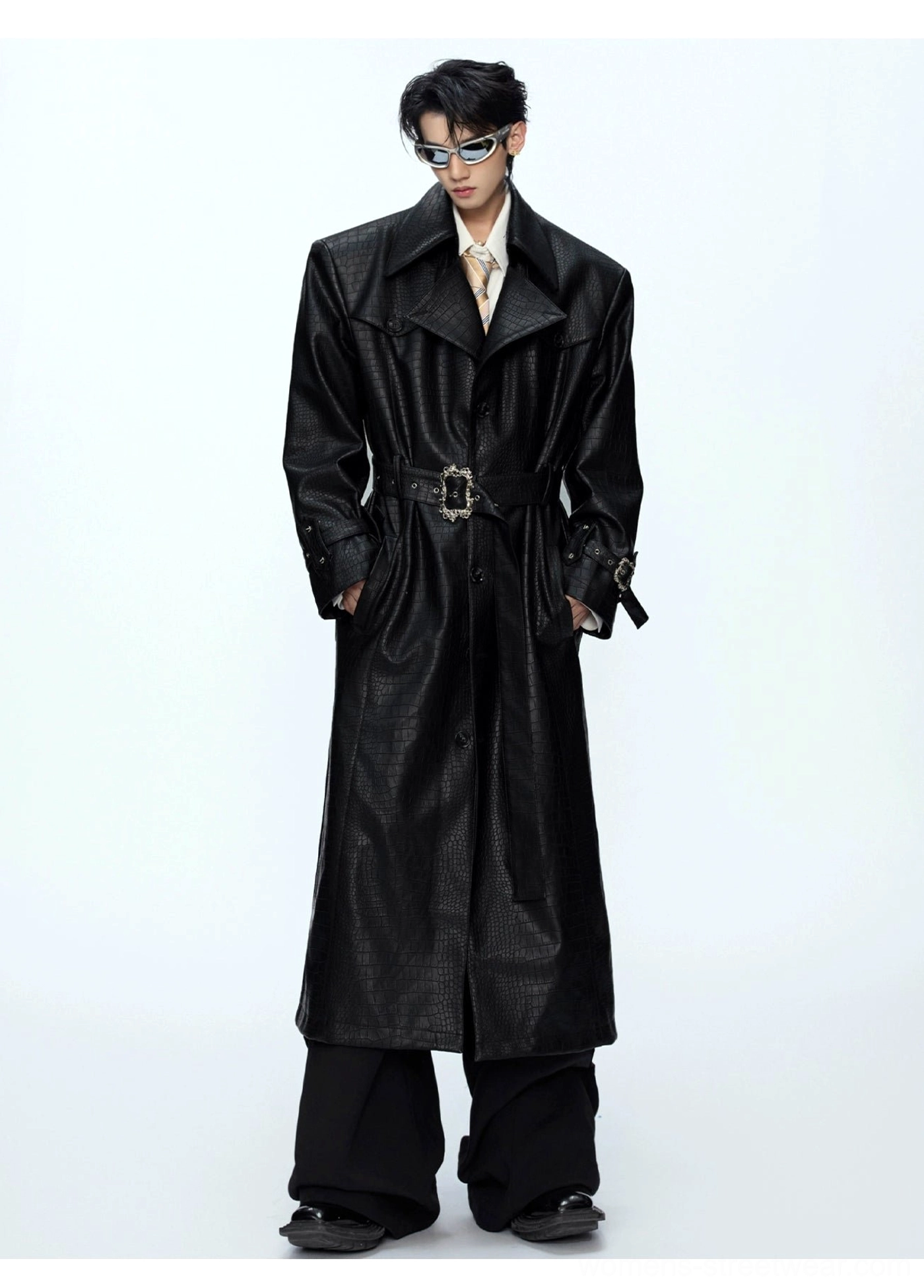Front full-body view of black croc-embossed leather trench coat with belted waist adjustable cuff straps and wide-leg trousers