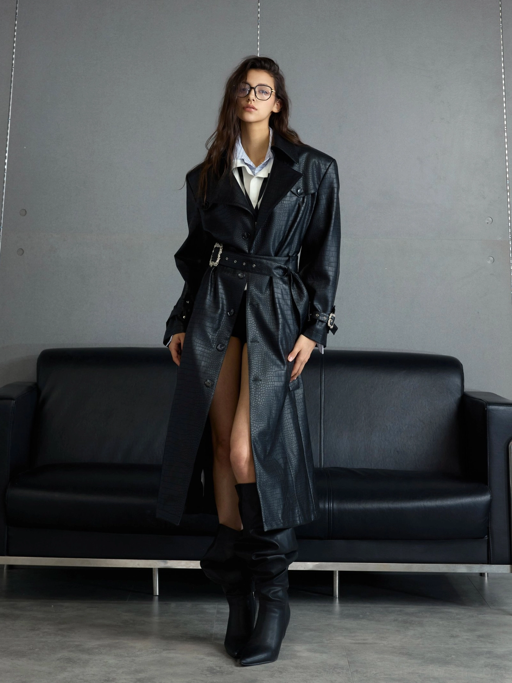 Front full-body view of black croc-embossed sheepskin leather belted trench coat styled with white shirt and black knee-high boots