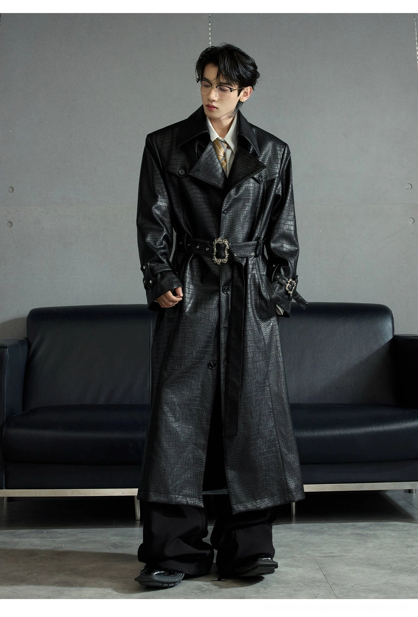 Black crocodile-embossed sheepskin leather trench coat front view showing tailored longline silhouette side pockets and cuff buckles