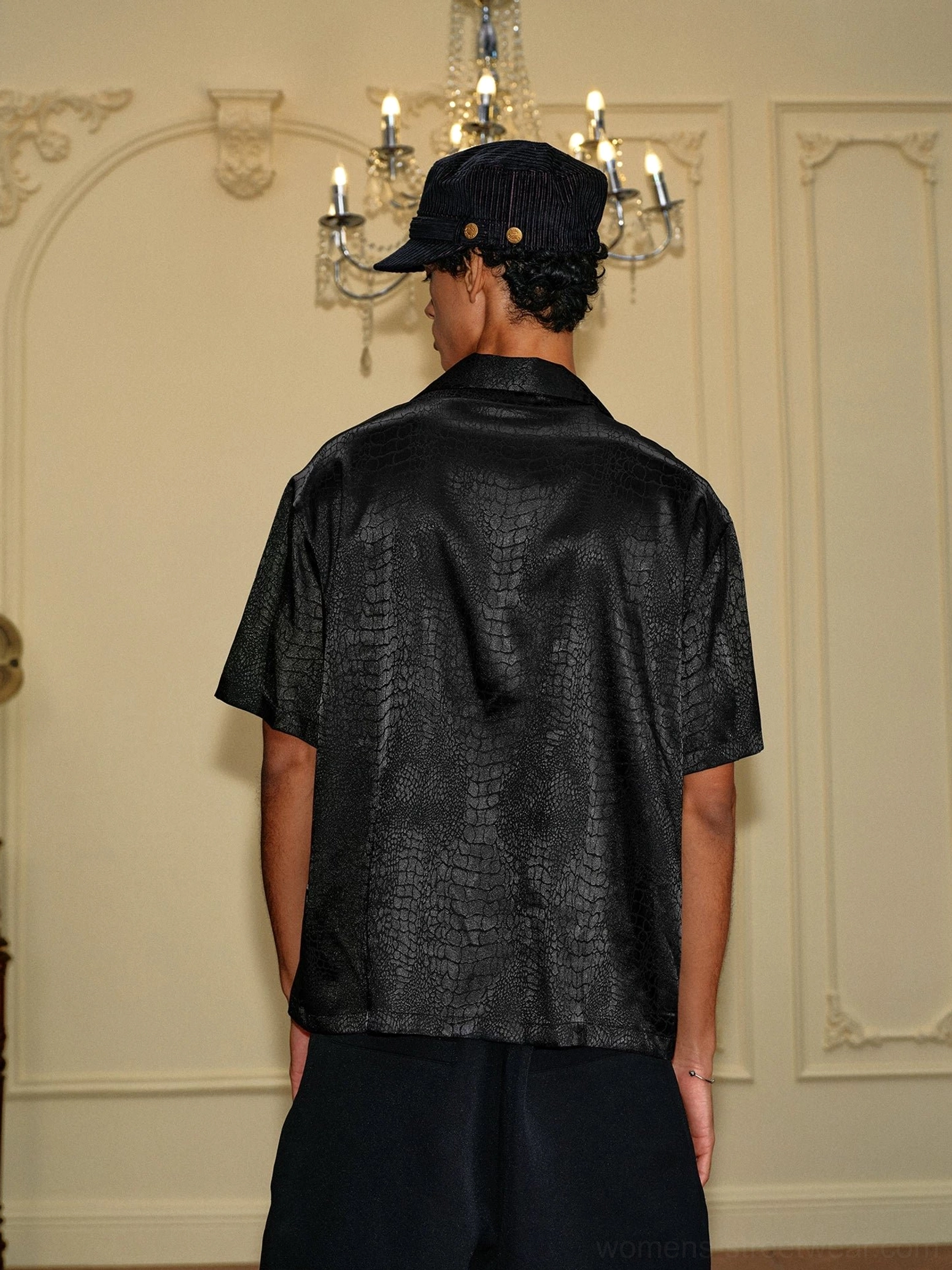 Back view of a relaxed black crocodile jacquard satin short sleeve shirt showing the full textured drape and loose streetwear silhouette