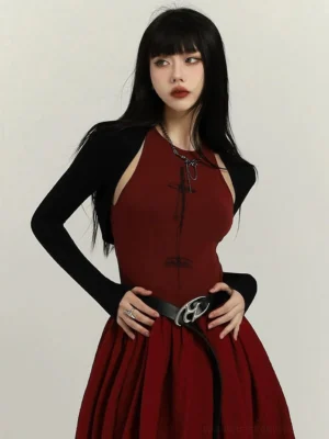Black cropped bolero cardigan coat layered over a wine red halter maxi dress in a front close-up streetwear outfit