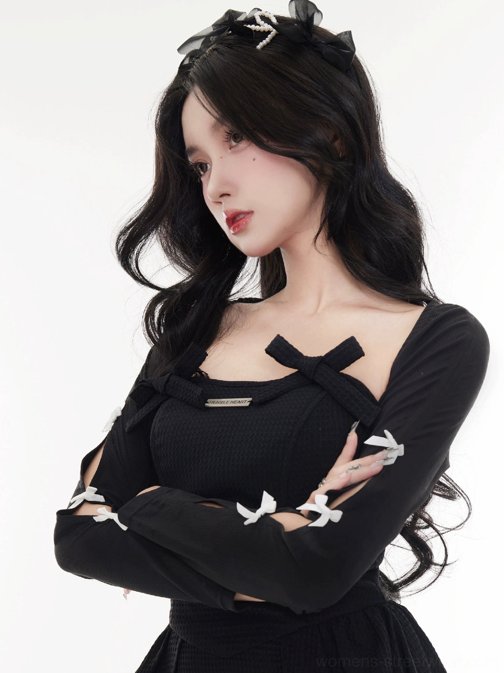 Front view of a black cropped bow cardigan featuring a square neckline, slim silhouette, and open sleeve details
