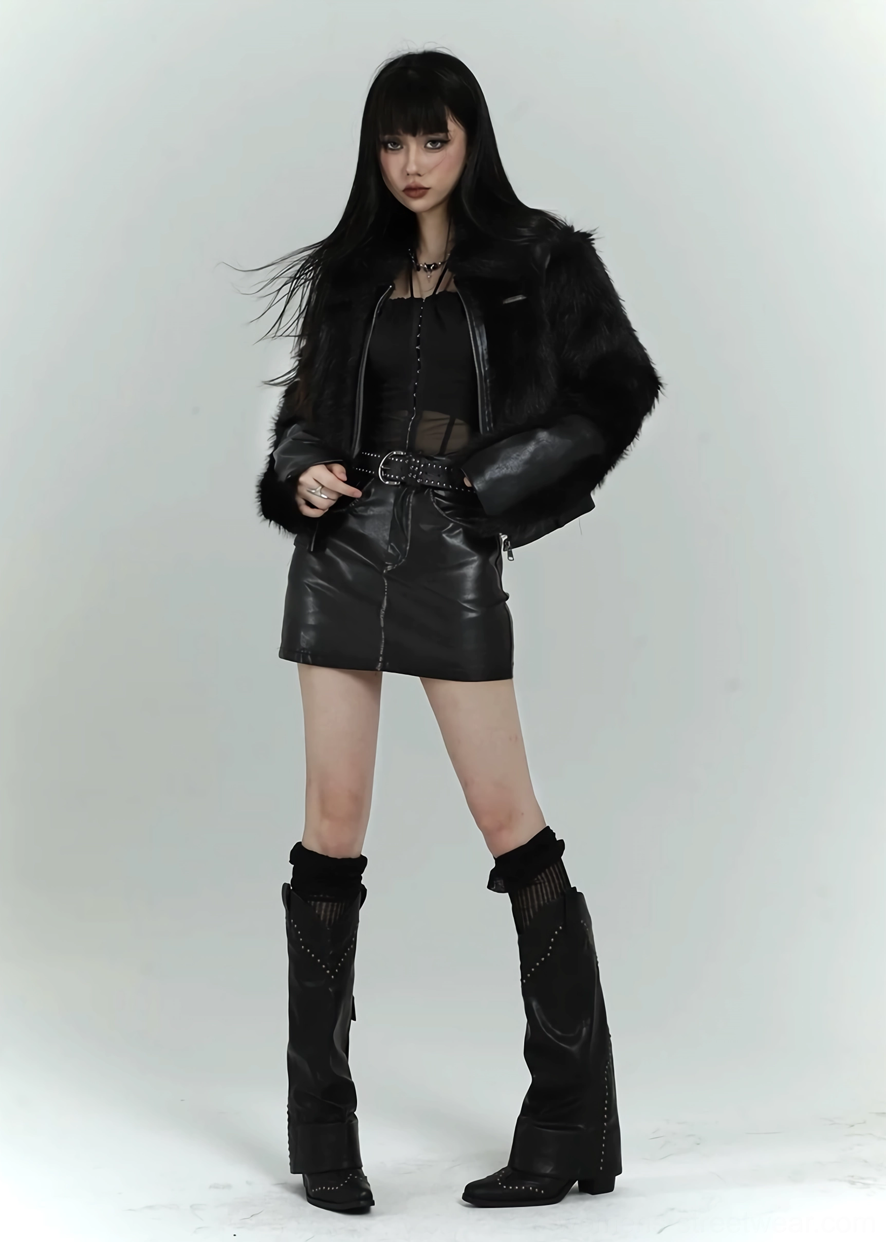 Front styling view of a black cropped faux fur bomber jacket paired with a mini skirt and tall western-inspired boots
