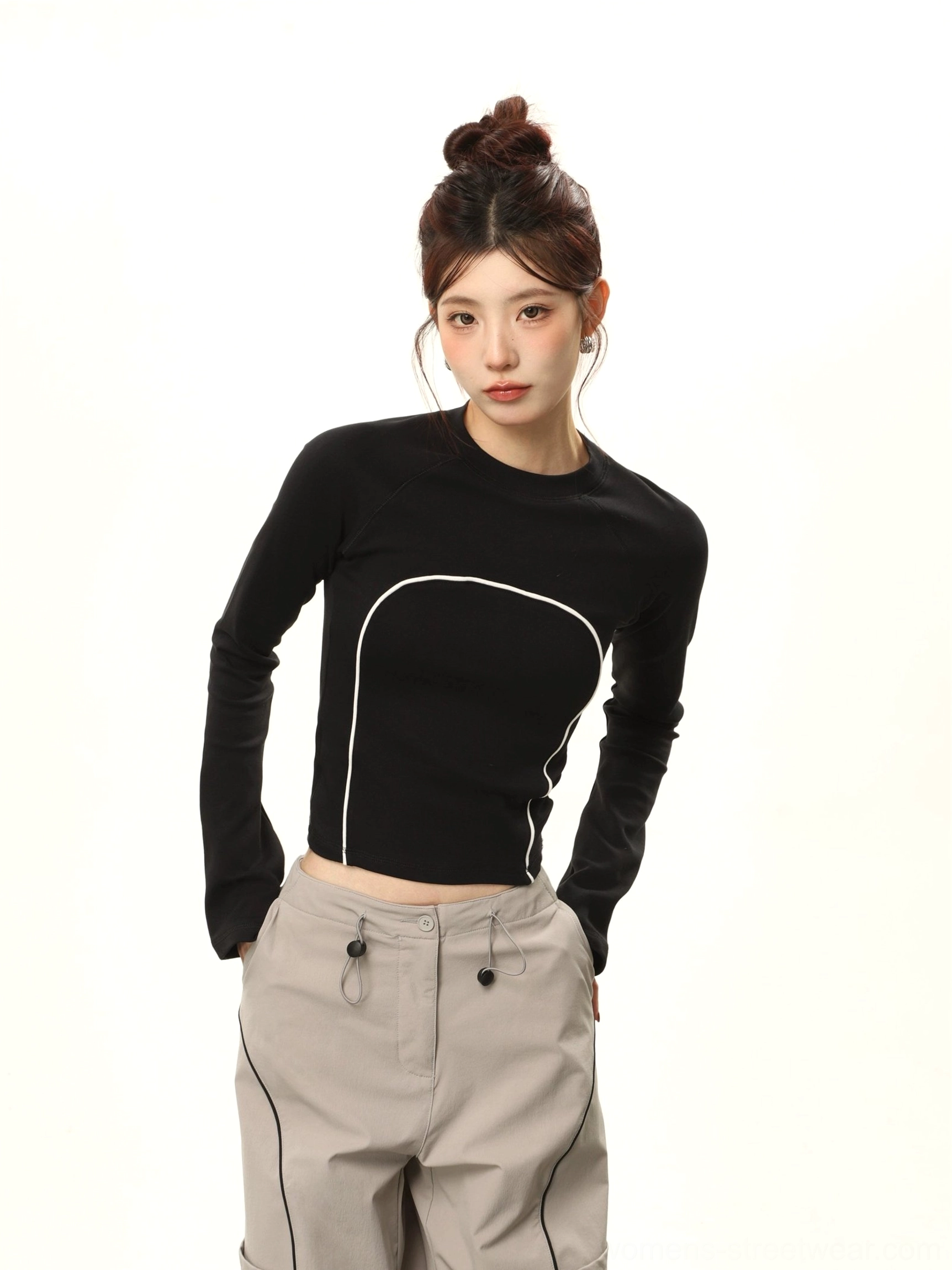 Black cropped fitted long sleeve top with white curved contrast stitching close-up streetwear outfit view