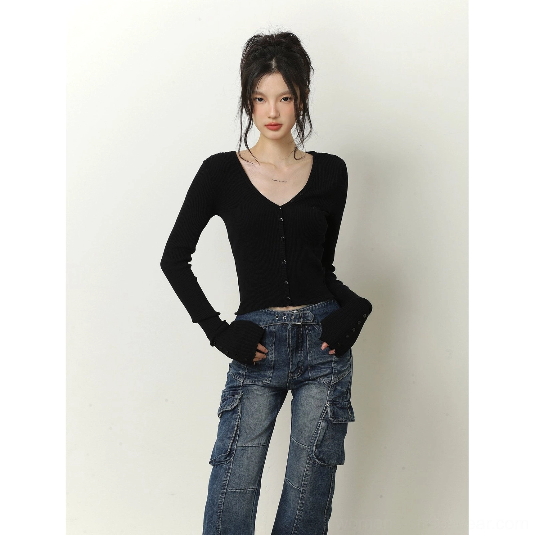 Black cropped ribbed knit cardigan with extended fingerless cuffs, V-neck, and front button closure styled with blue cargo jeans