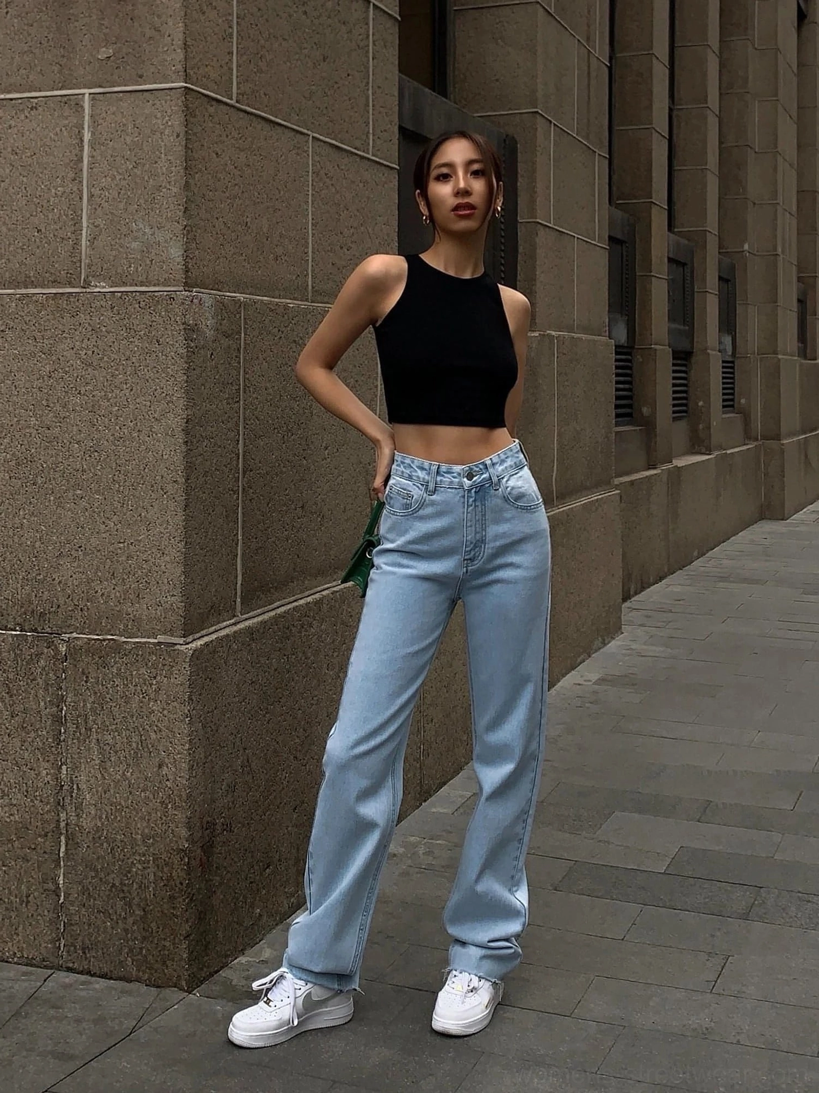 Black cropped tank top full body front view - fitted crew neck sleeveless silhouette showing waistline paired with light blue wide-leg jeans and white casual sneakers on urban sidewalk outdoor backdrop