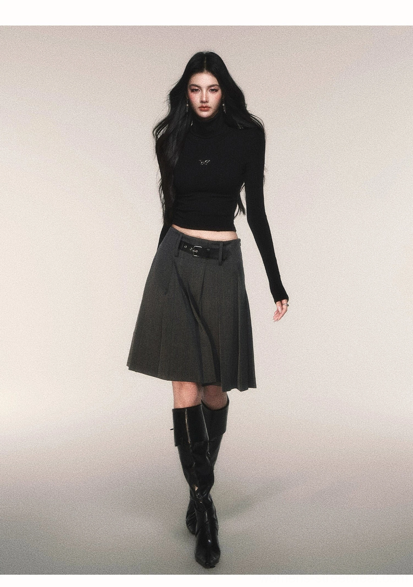 Black cropped turtleneck knit top with long sleeves styled with pleated skirt and knee-high leather boots
