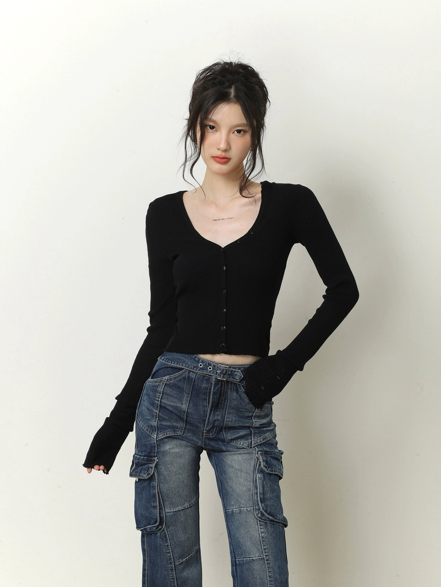 Black cropped V-neck ribbed knit cardigan with fingerless long sleeves and exposed waist styled with blue cargo jeans