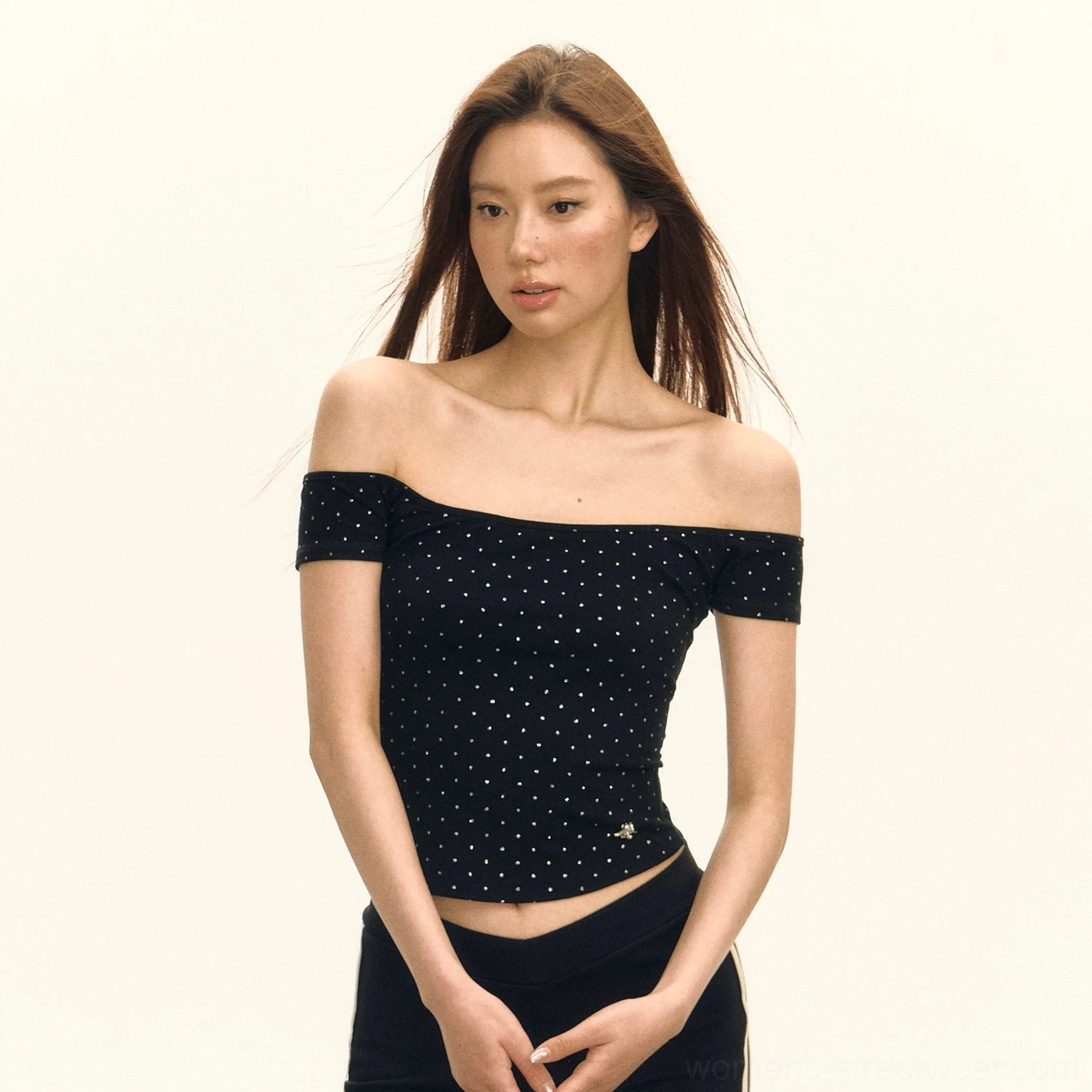 Black crystal embellished off shoulder ribbed cropped top with fitted silhouette and hem charm styled with black track pants