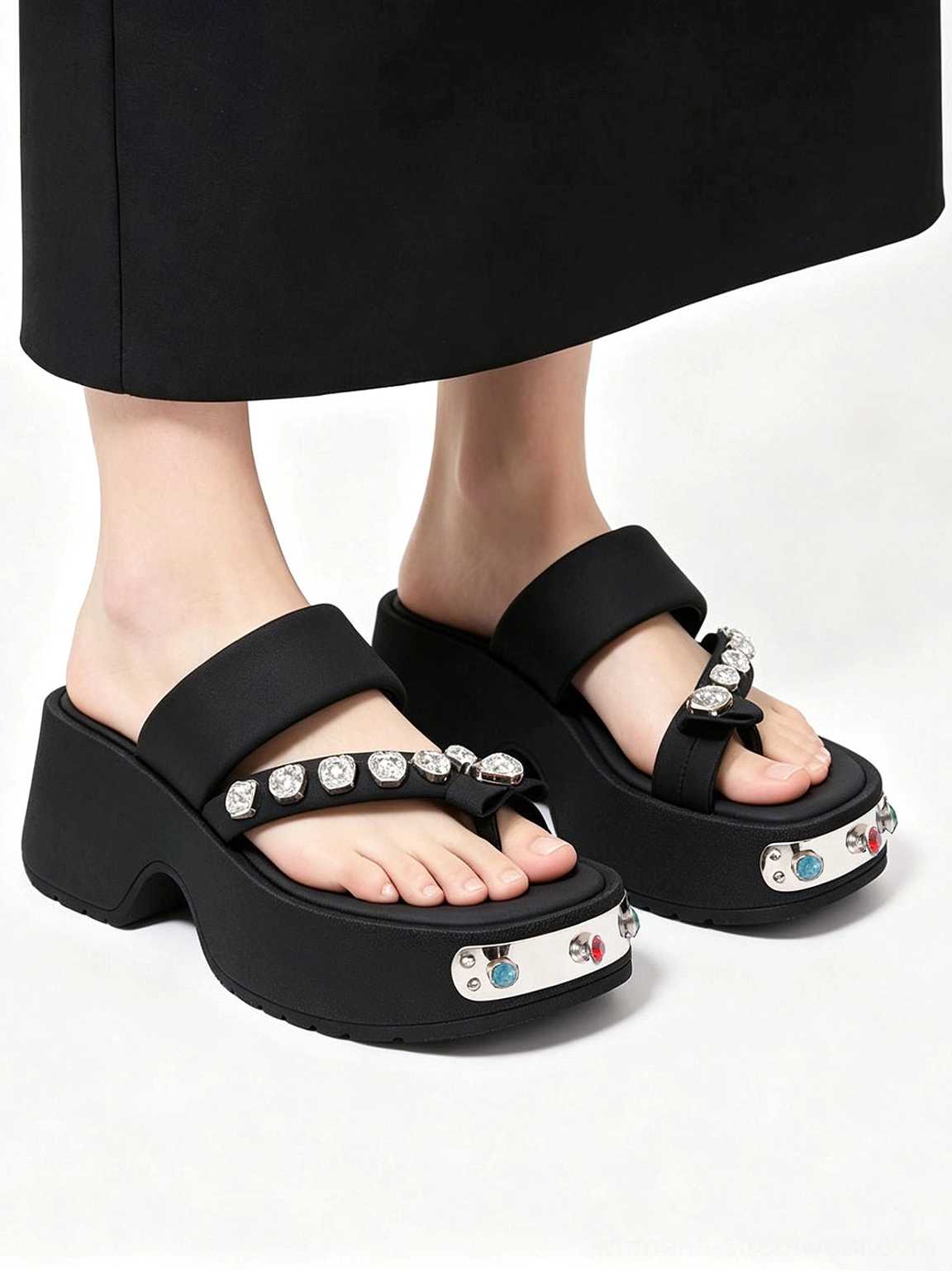 Front overhead view of black crystal platform slides worn with a long black skirt, featuring symmetrical silver toe plates and colorful crystal embellishments
