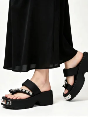 Model wearing black crystal platform thong sandals with a long black midi skirt, showing the elevated sole, jeweled toe strap, and modern Korean streetwear styling