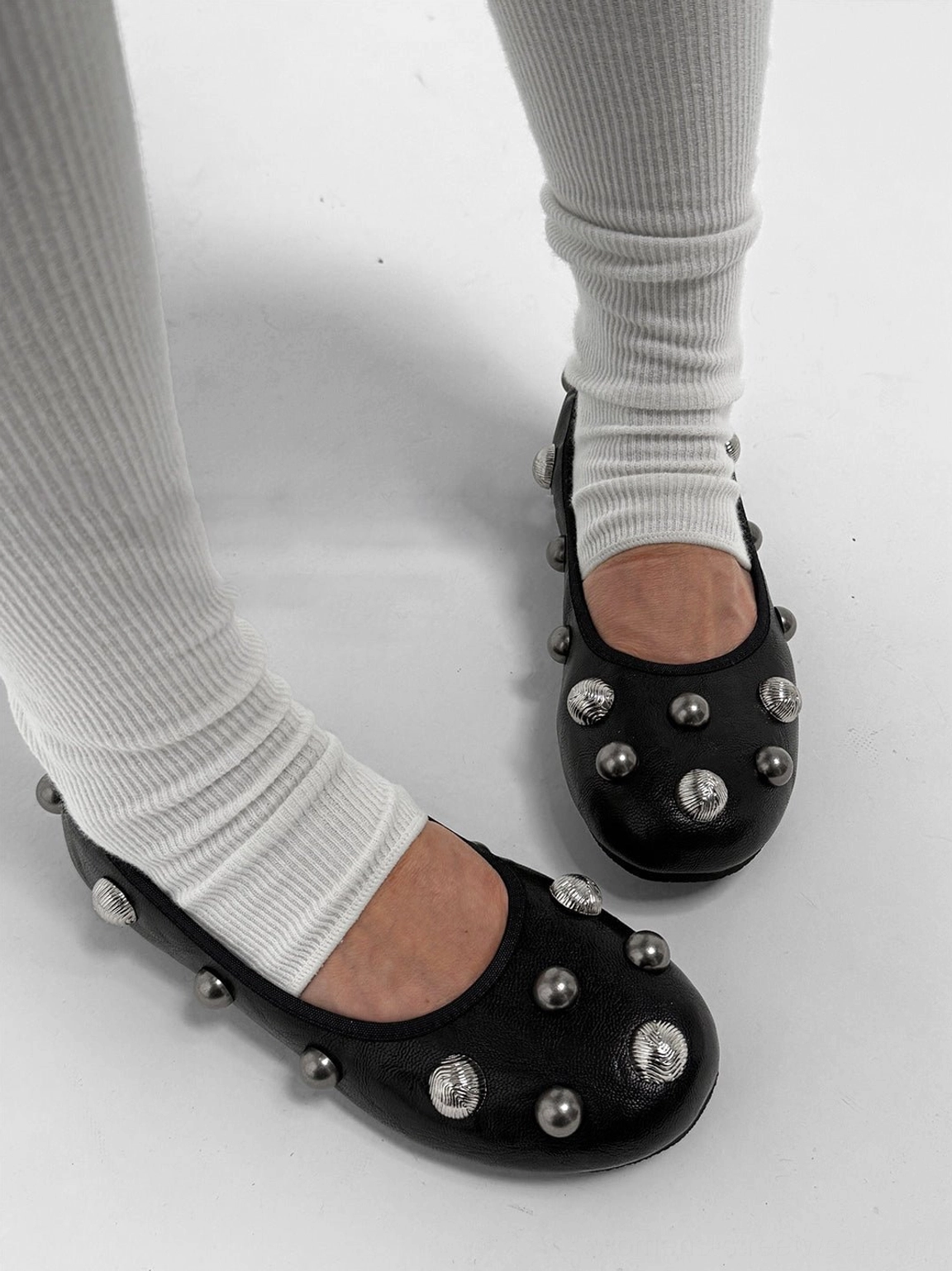 Three-quarter view of black crystal stud ballet flats with silver embellishments across the toe, vamp, and heel counter