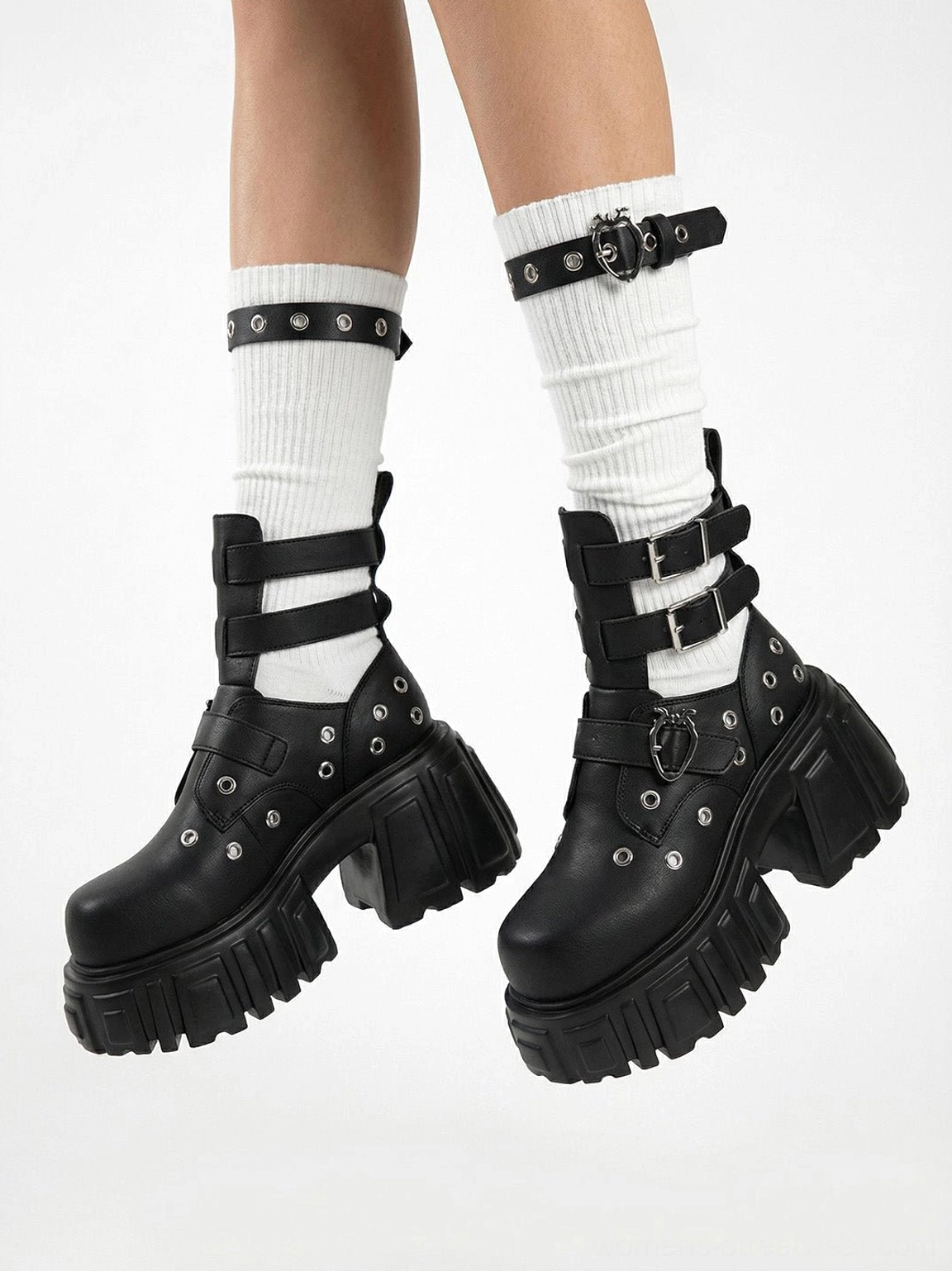 Close-up of black cutout platform boots styled with white ribbed socks adjustable ankle buckles metal eyelets and thick lug soles