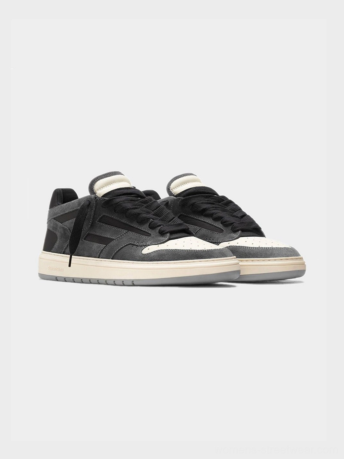 Pair of black and dark gray suede-look low-top casual sneakers with off-white laces and rubber sole on gray background