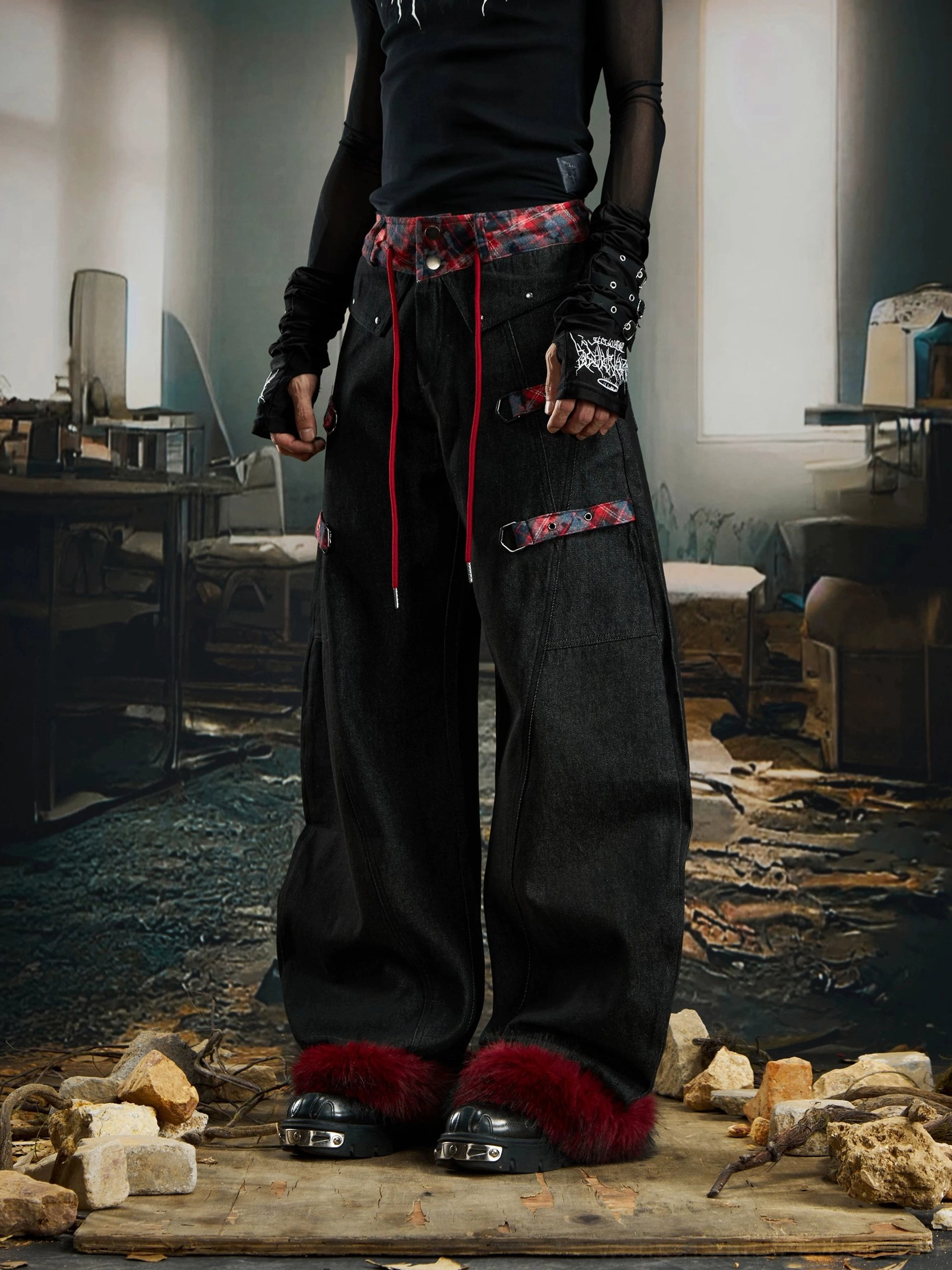 Front view of oversized black denim cargo pants with red tartan waist drawstrings side straps and detachable dark red faux-fur hems