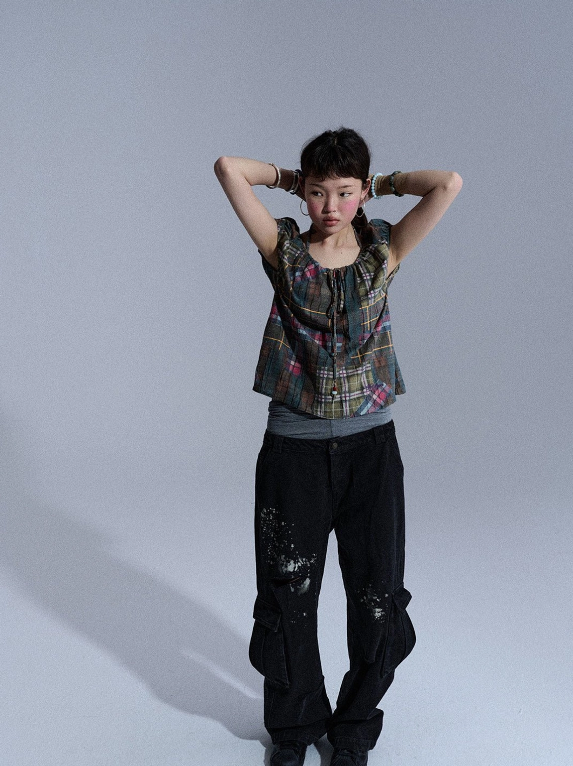 Rear view of black distressed cargo jeans with wide-leg cut, paint-splatter pattern, ripped details, and multiple pockets