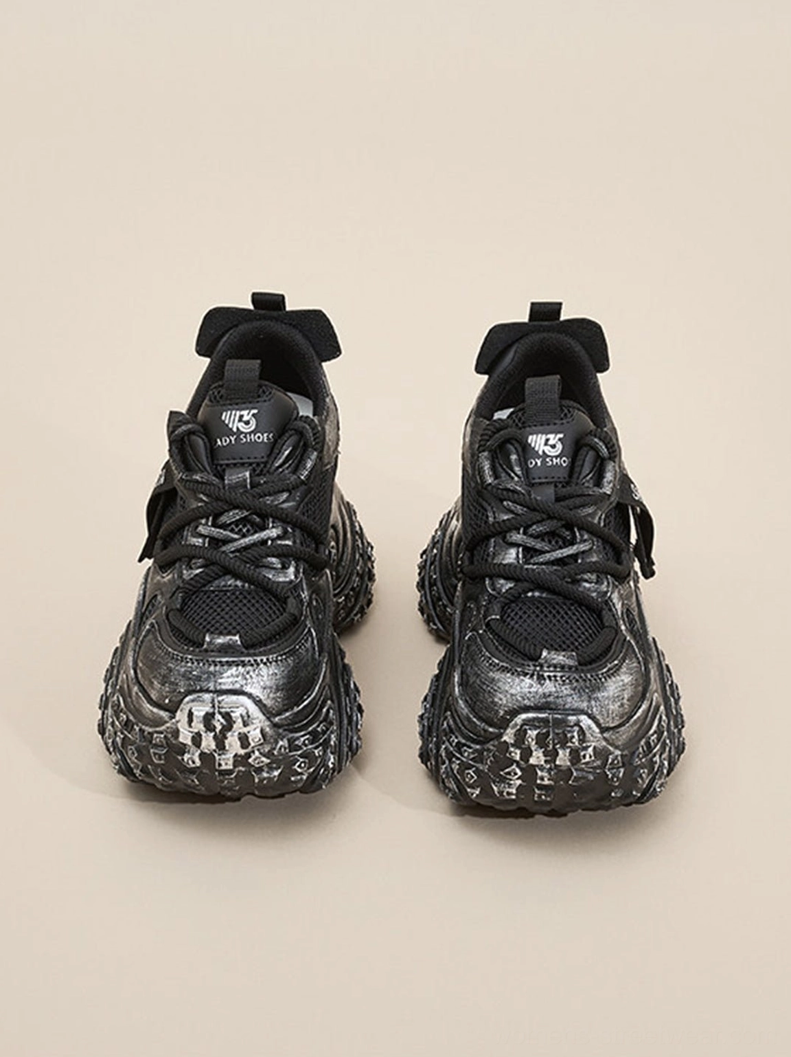 Front view of black distressed chunky platform sneakers showing mesh toe box laces and padded tongue detail
