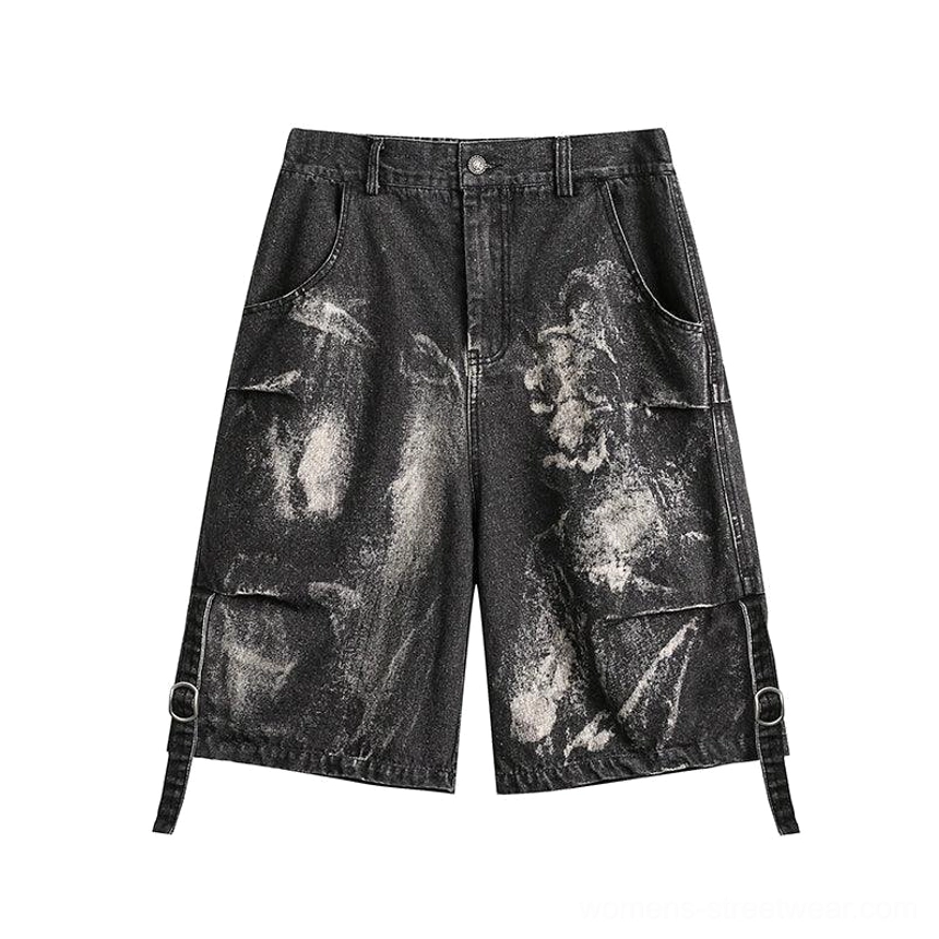Front flat lay of black distressed denim cargo Bermuda shorts showing button waistband, wide legs, side cargo pockets, bleached denim pattern, and buckle strap details
