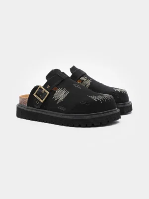 Black distressed denim platform mule clogs with antique brass buckle, scratch embroidery, cork footbed, and chunky rubber outsole