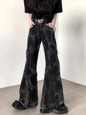 Front low-angle view of black distressed flared jeans with diagonal frayed seams, washed denim finish, wide-leg silhouette, belt, and platform boots