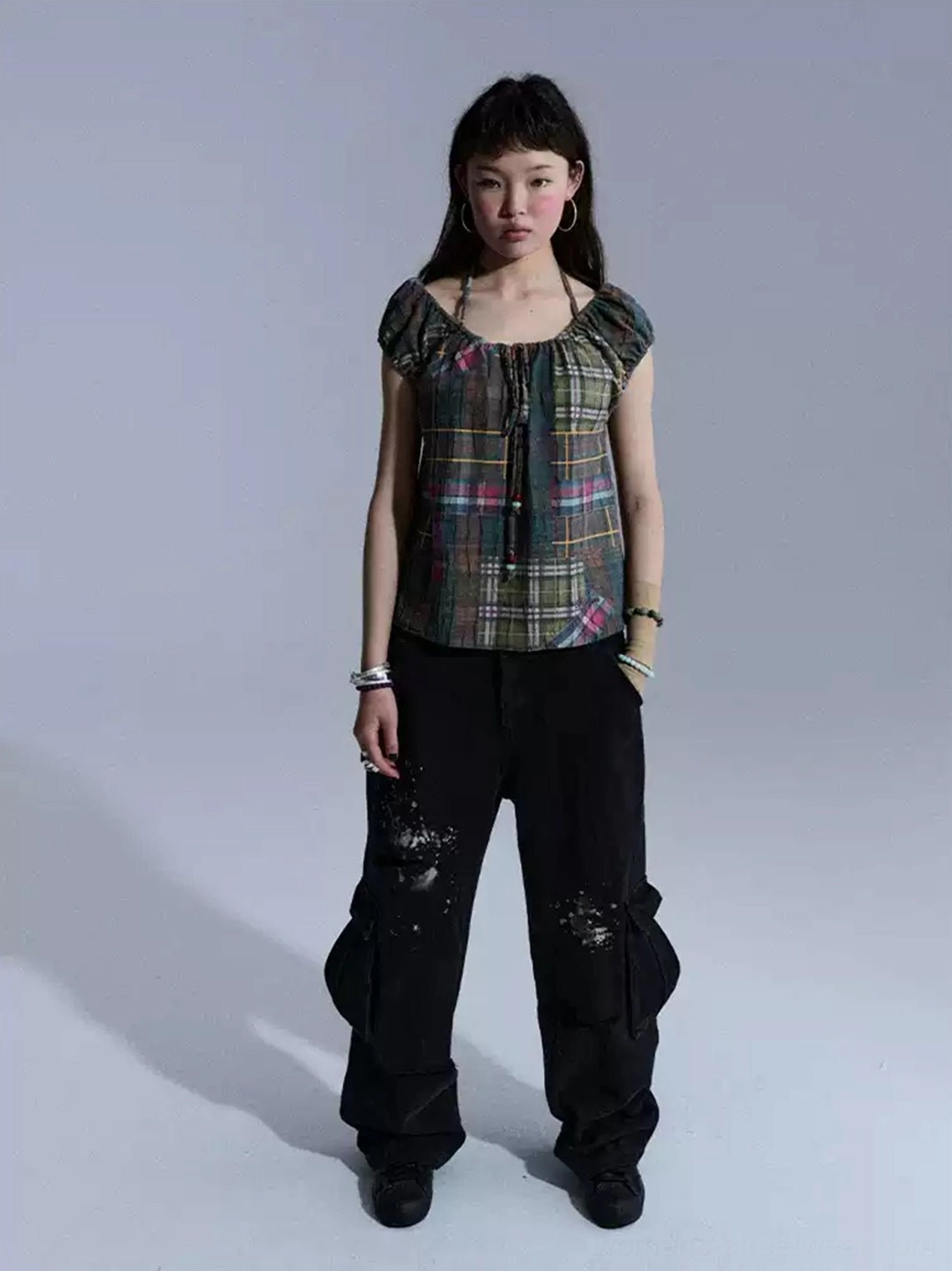 Black distressed paint-splattered cargo pants with ripped details, relaxed wide-leg fit, and functional side pockets