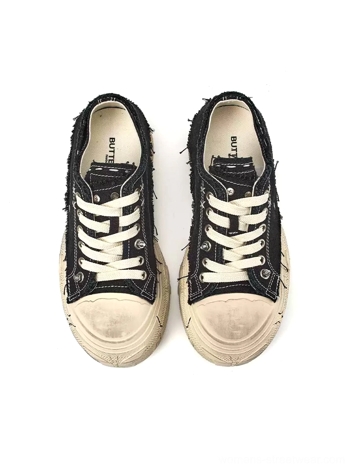 Front view of paired black distressed platform canvas sneakers with vintage off-white toe caps and classic lace-up design