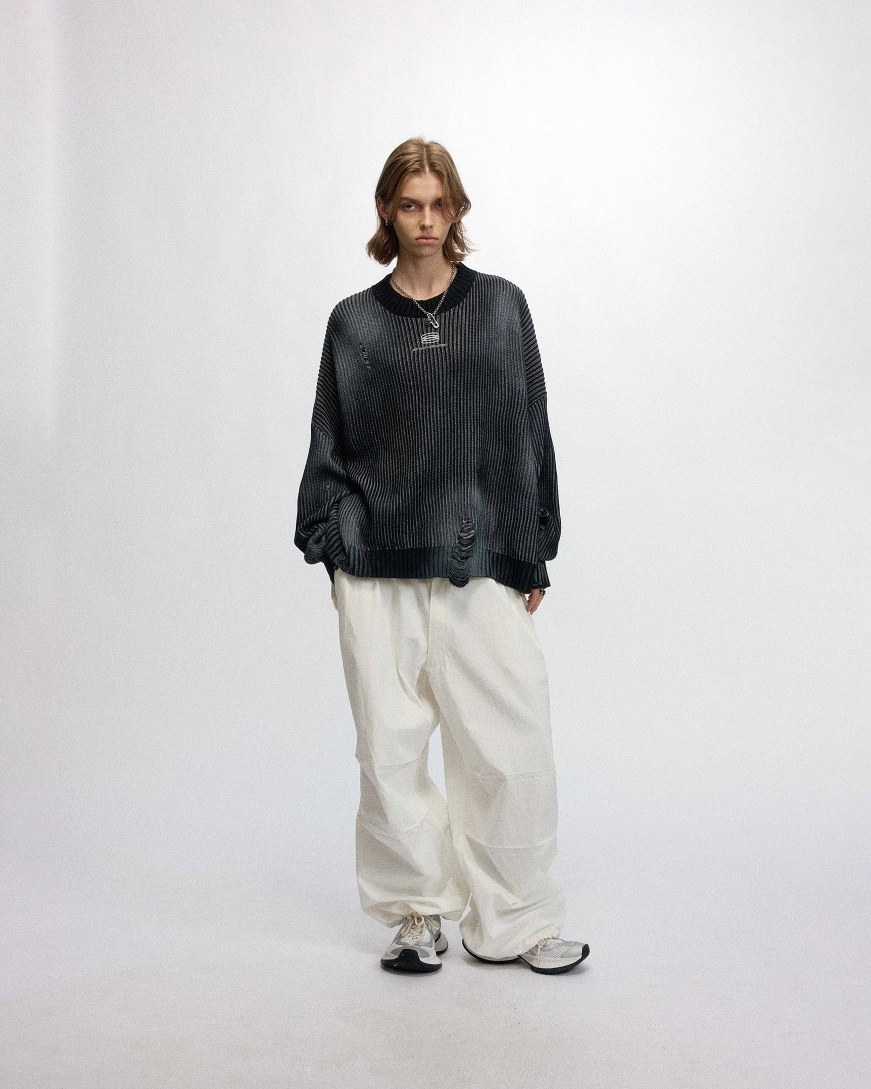 Black distressed ribbed knit sweater with relaxed drop shoulders and modern unisex streetwear silhouette