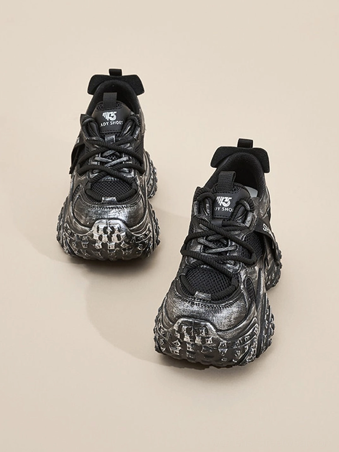 Rear view of black and silver distressed sculptural platform sneakers showing heel pull tabs and chunky sole structure