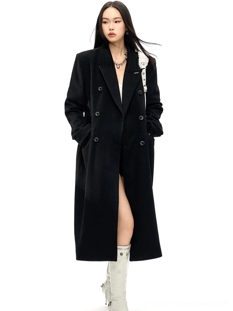 Black double-breasted long wool coat styled in a walking pose showing the front opening and tailored fit
