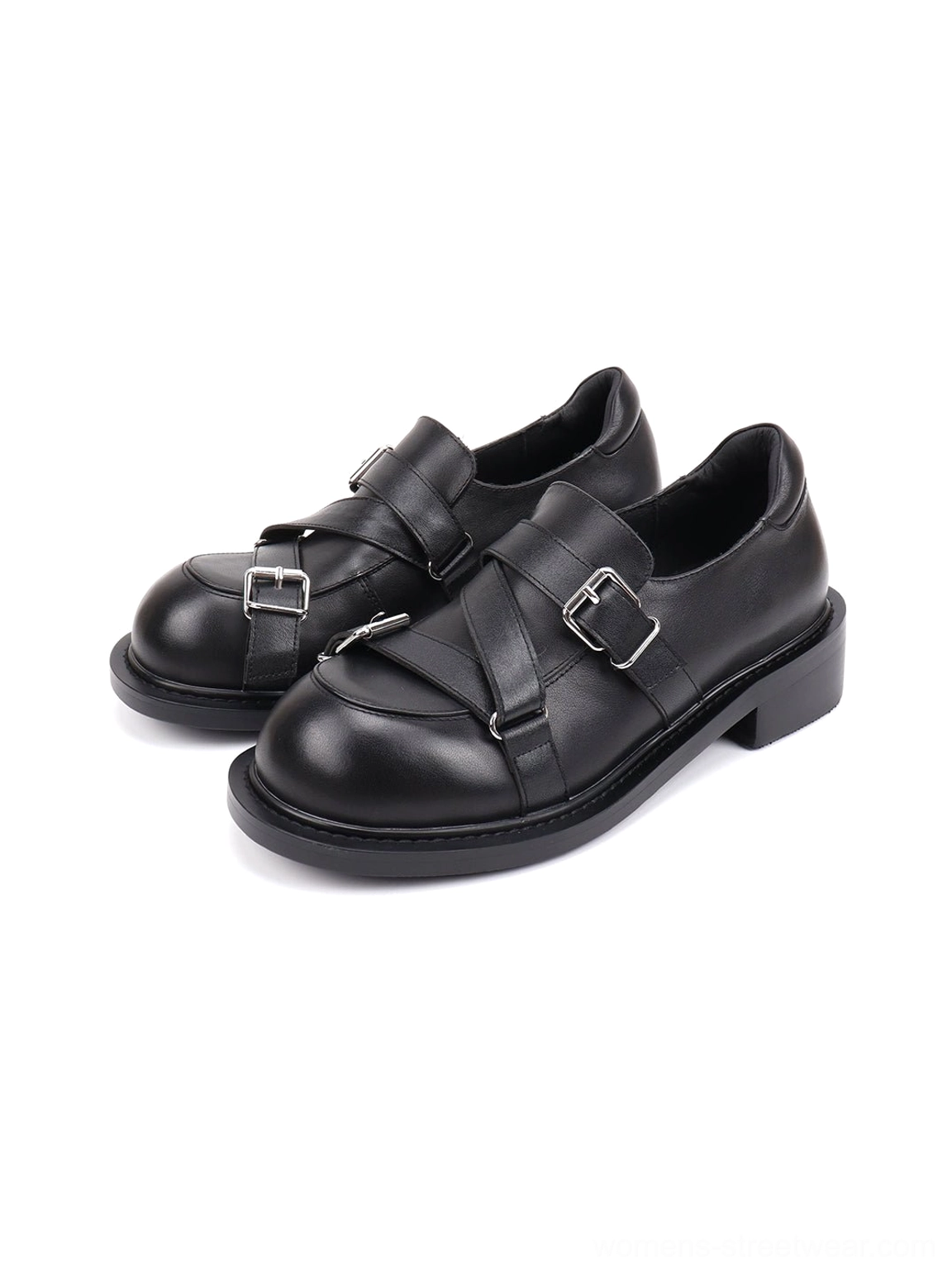 Black double-buckle monk-style loafers displayed from a side angle with glossy leather-look finish, silver hardware, and chunky block heels