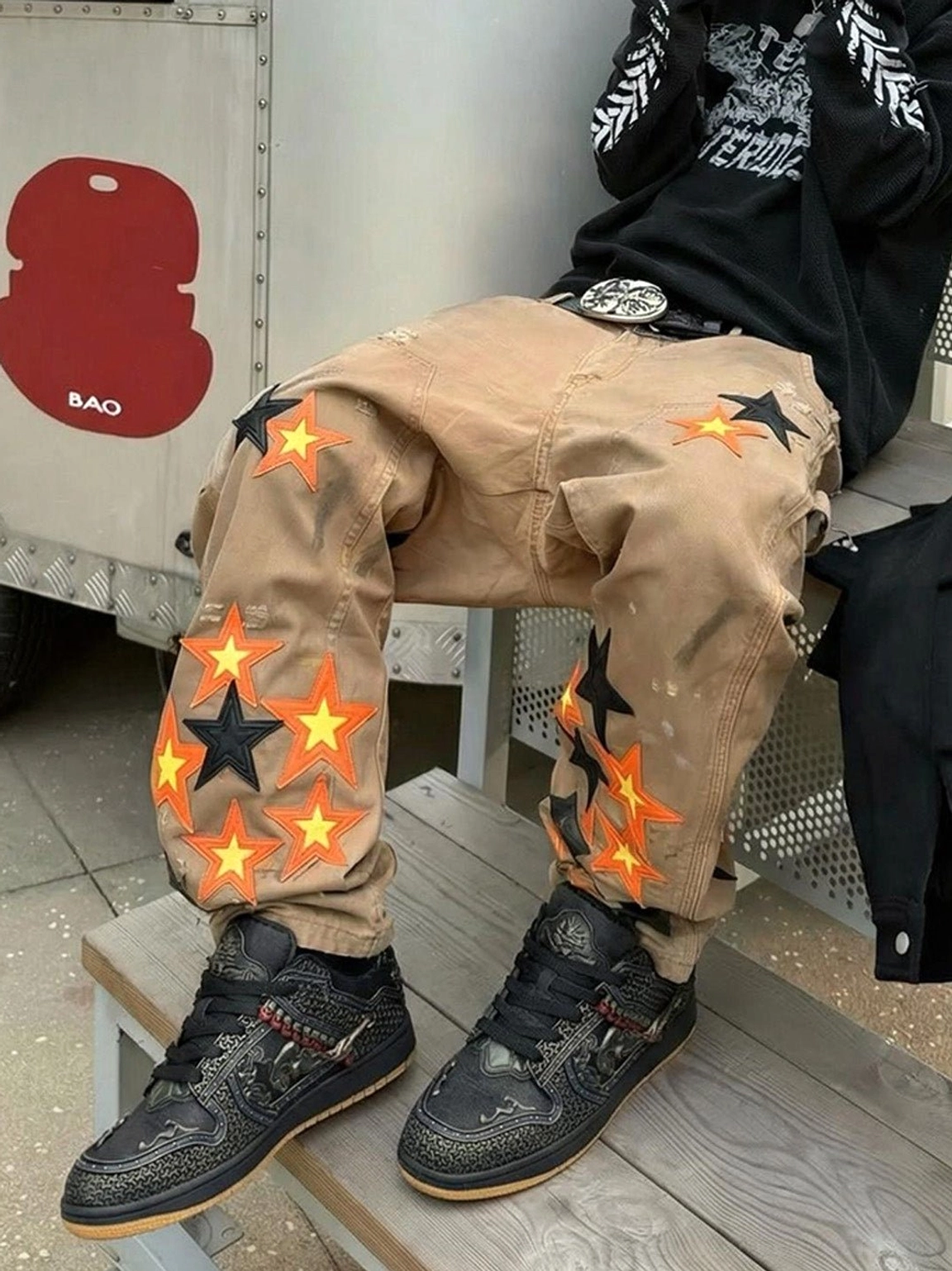 Black dragon embroidered sneakers worn with casual khaki pants, showing the red beaded strap and bronze side ornament