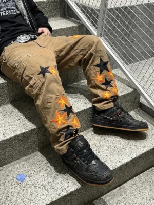 Black dragon low-top streetwear sneakers styled with relaxed khaki star-print pants in an outdoor urban setting