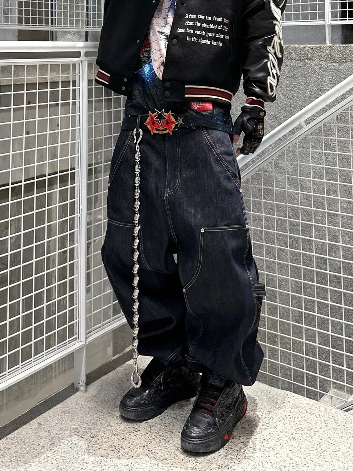 Black dragon relief platform sneakers styled with baggy dark denim, a varsity bomber jacket, and a metal wallet chain in an industrial streetwear outfit