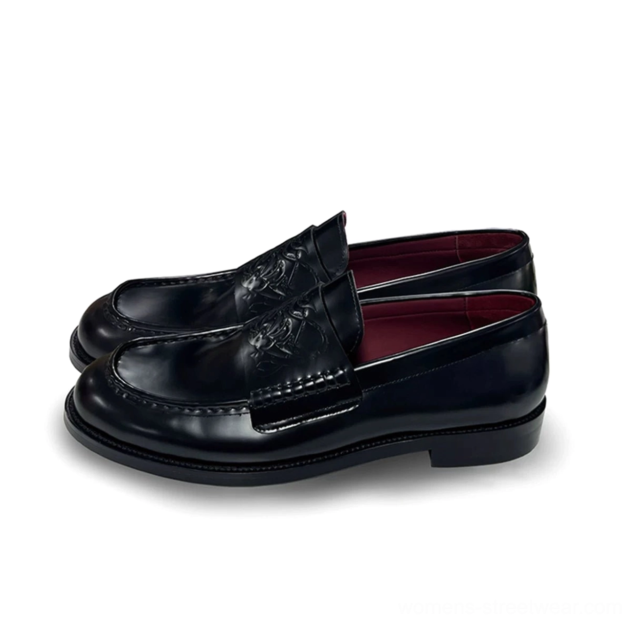 Black embossed leather loafers shown from a front three-quarter angle with low stacked heels, precise stitching, square toes, and burgundy lining