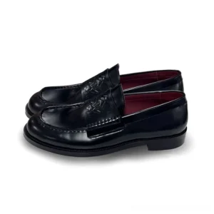 Black embossed leather loafers in a three-quarter side view showing the square-toe shape, low stacked heel, leather stitching, and burgundy lining