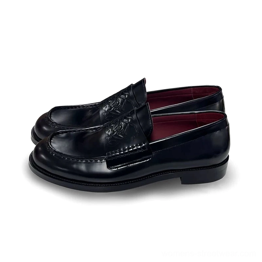 Black embossed leather loafers in a three-quarter side view showing the square-toe shape, low stacked heel, leather stitching, and burgundy lining