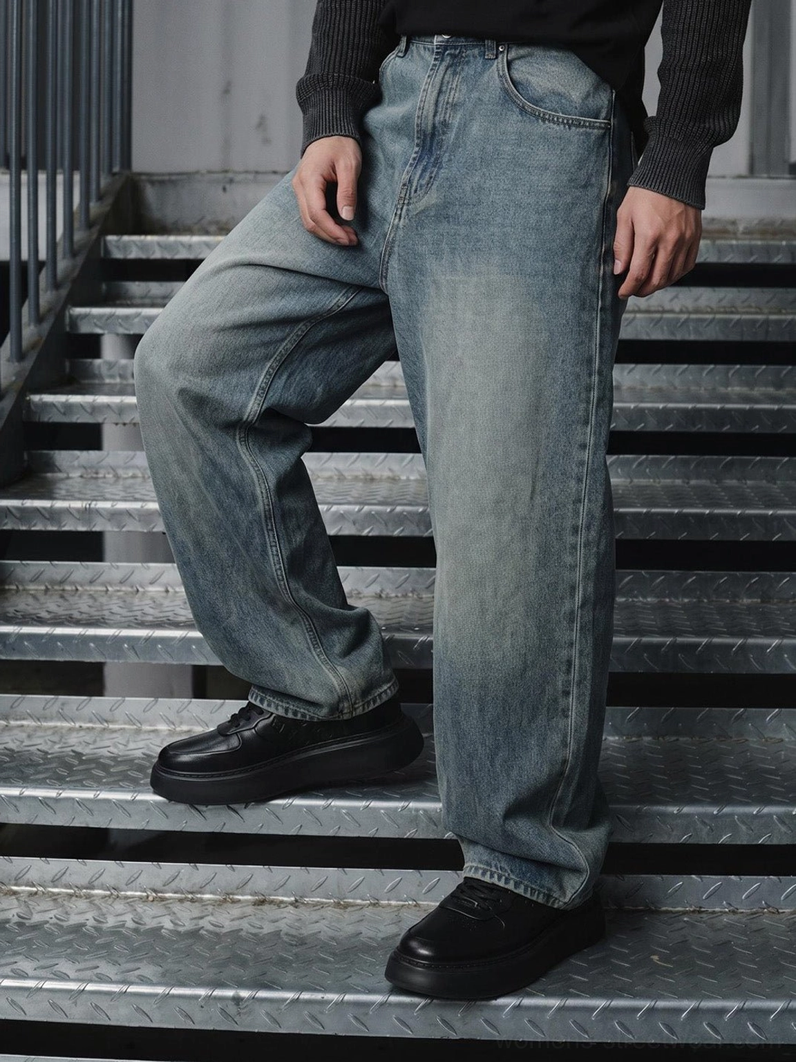 On-foot side view of black embossed platform low-top sneakers with casual denim streetwear outfit