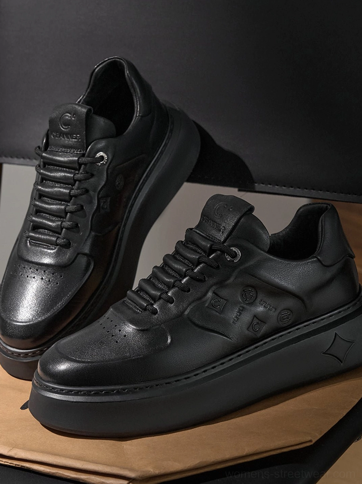 Pair of black embossed platform low-top sneakers showing perforated lace eyelets and tonal leather-look panels