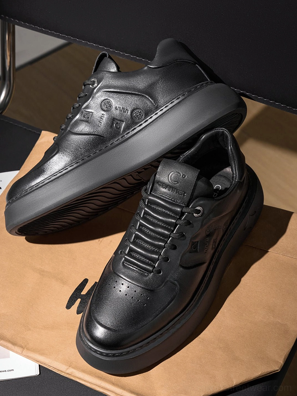 Black embossed platform low-top sneakers flat lay showing tonal textured uppers and stacked shoe profile