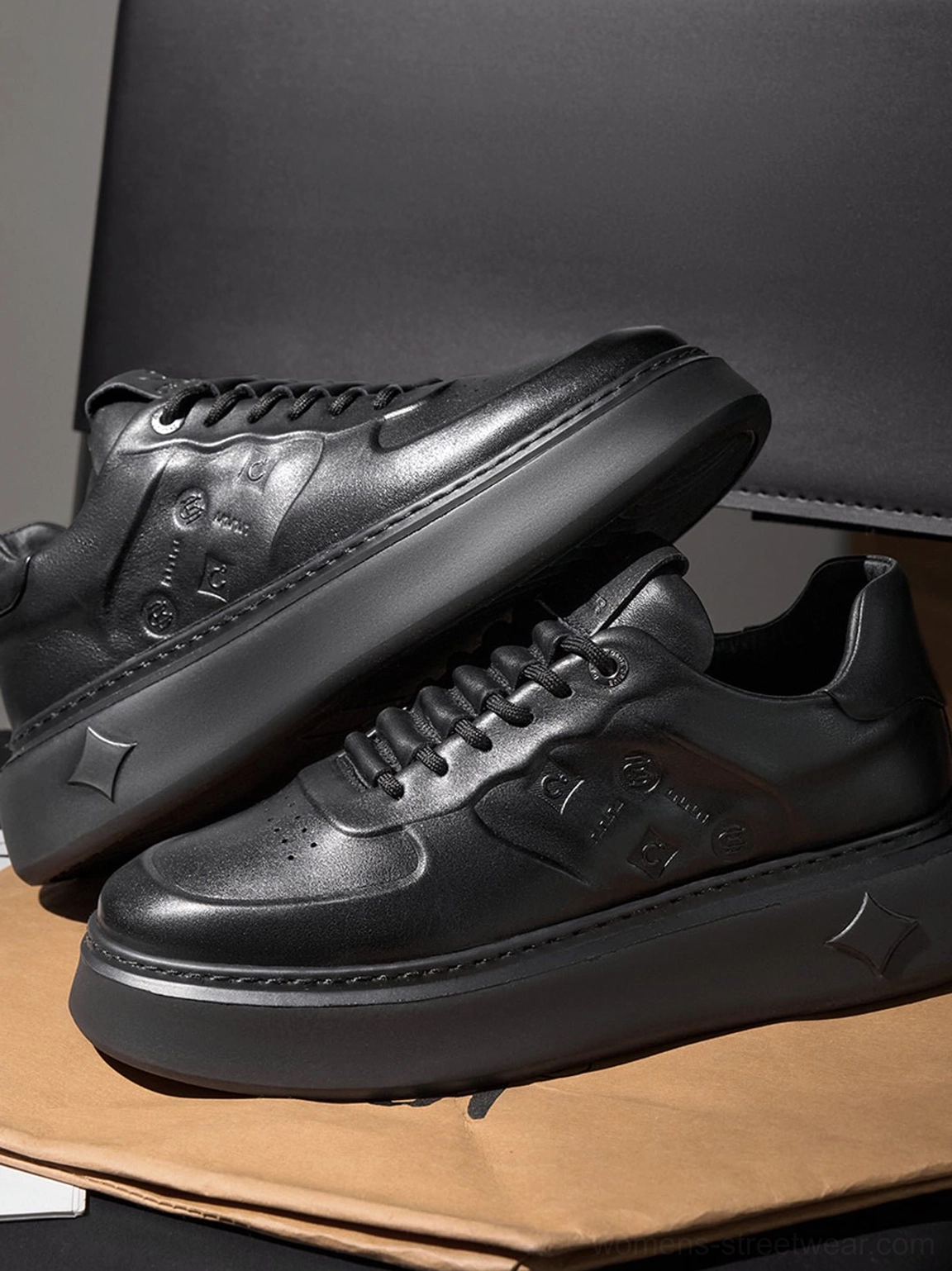 Close-up side view of black embossed platform low-top streetwear sneakers with thick matte platform sole