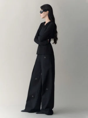 Side full-body view of black embroidered bow charm wide-leg streetwear trousers with a relaxed floor-length silhouette