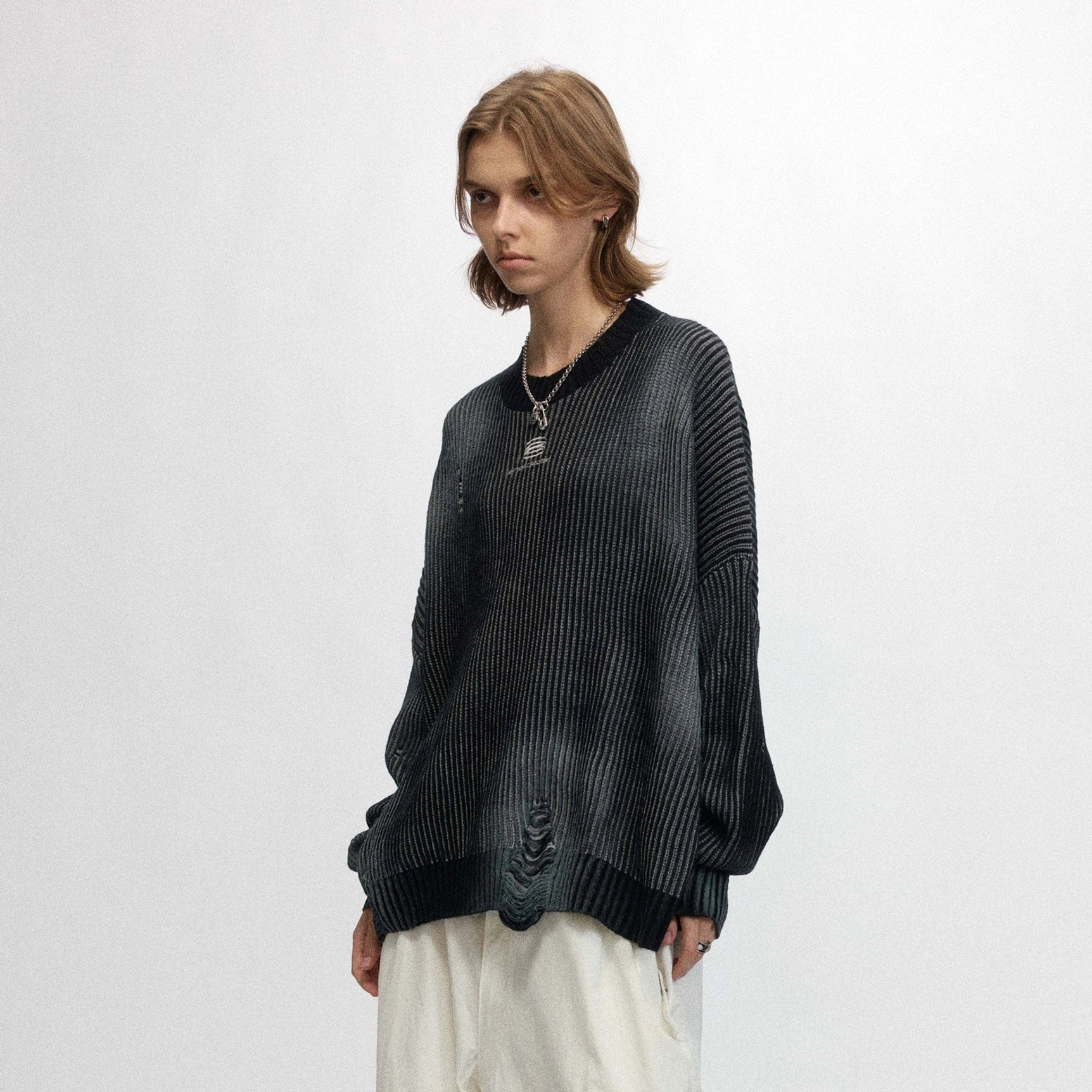 Front view of a female model wearing a black faded ribbed logo sweater with crew neck and distressed hem details