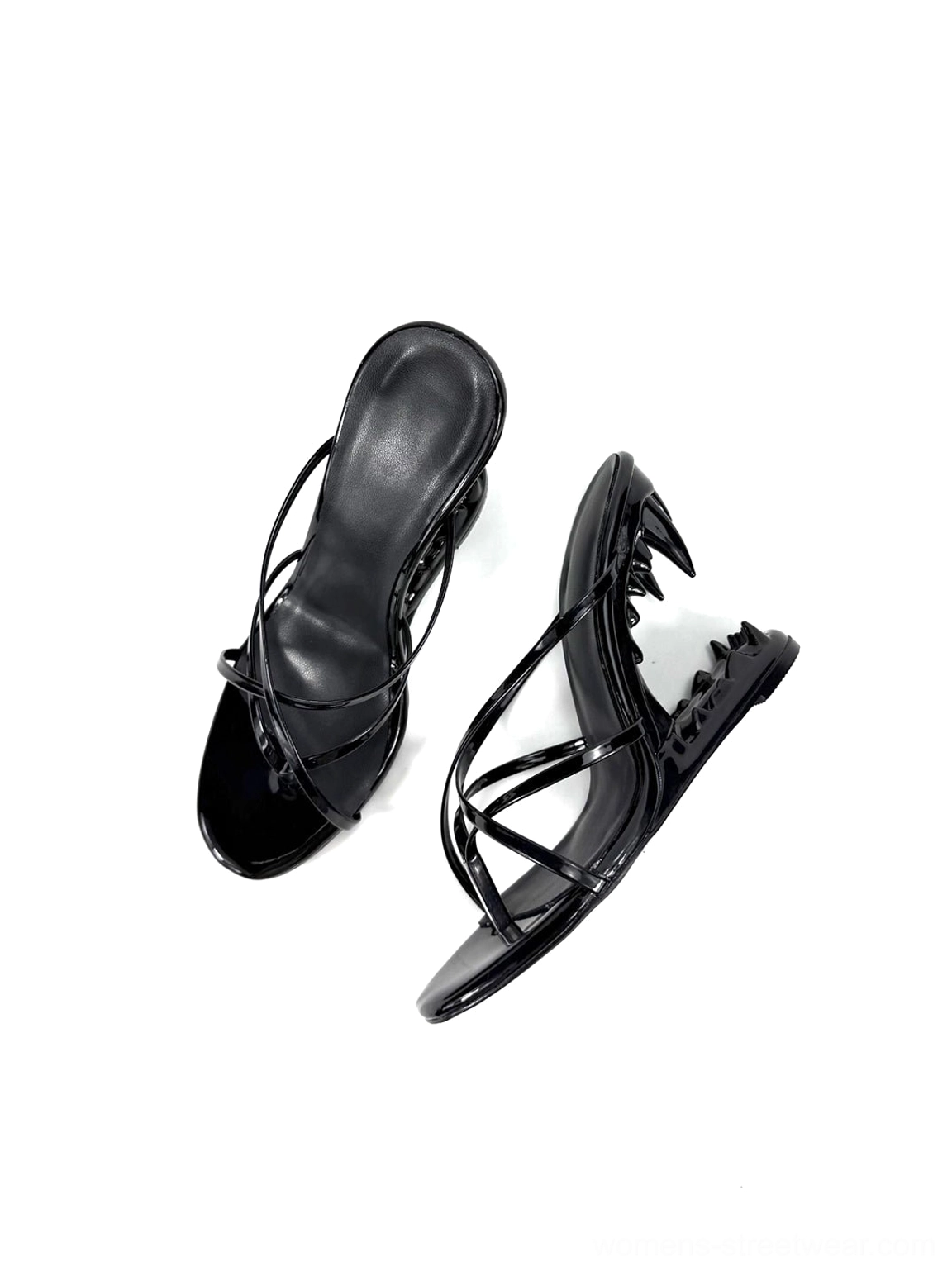 Pair of black glossy open-toe mule sandals showing both profiles and distinctive fang-shaped heels