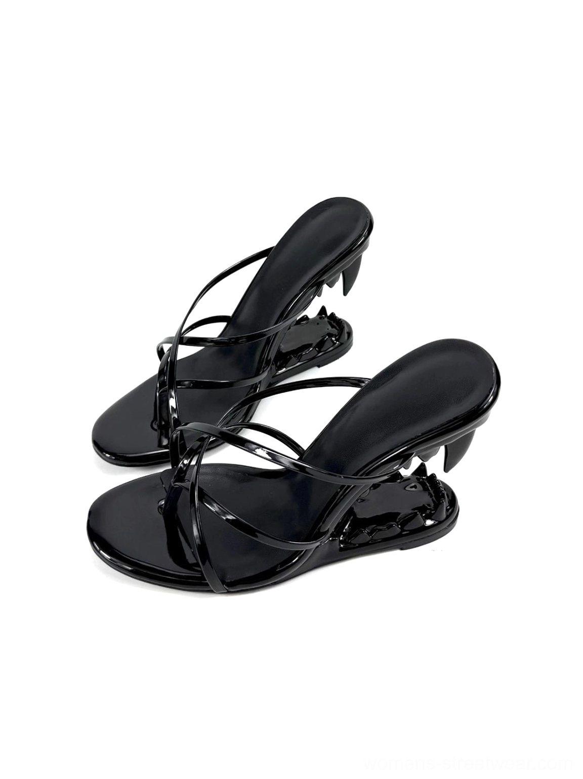 Top angled flat lay of glossy black crossover strap mule sandals with exposed sculpted fang-profile heels