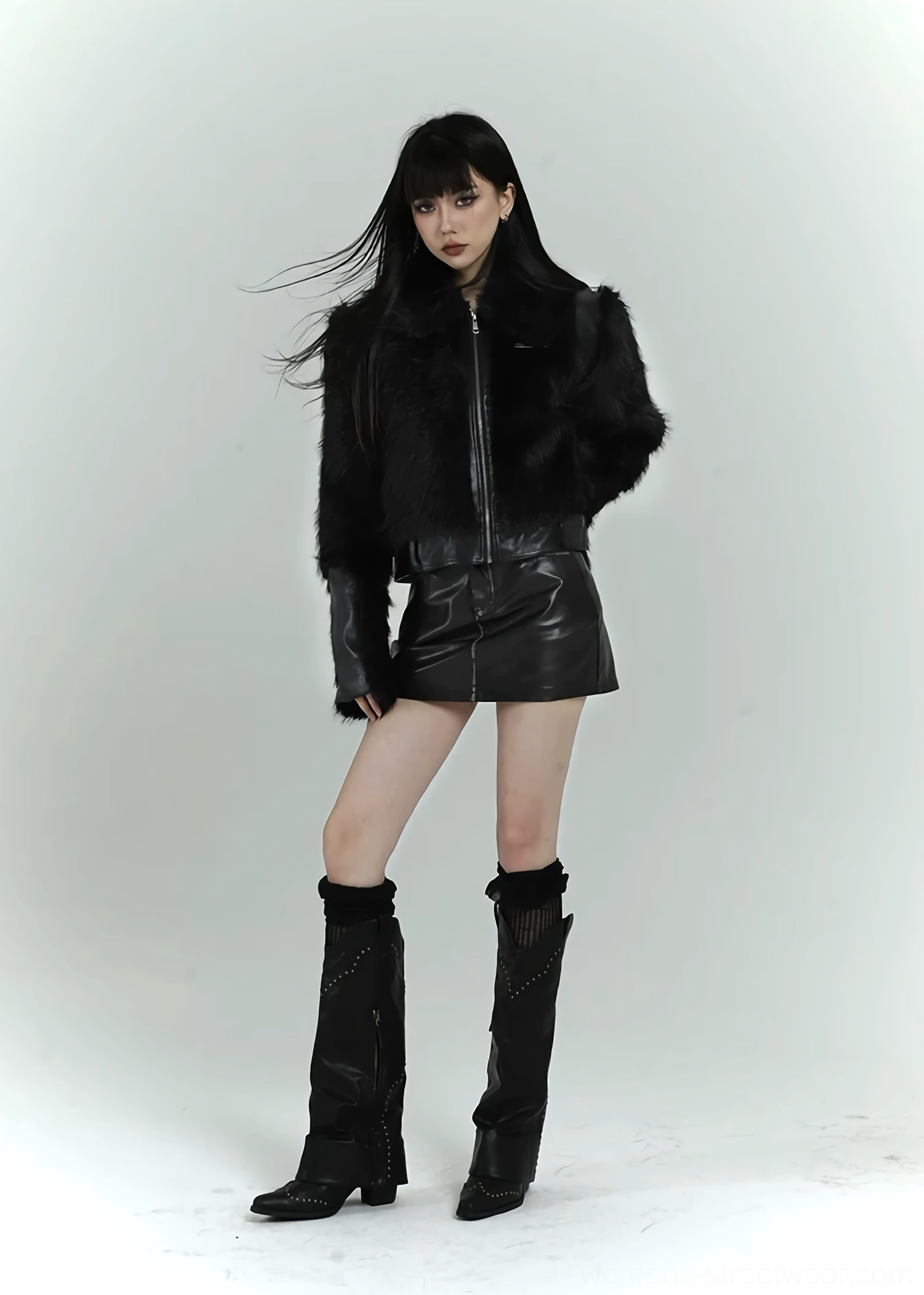 Full front side view of a black faux fur cropped bomber jacket with a metal zipper and monochrome streetwear outfit