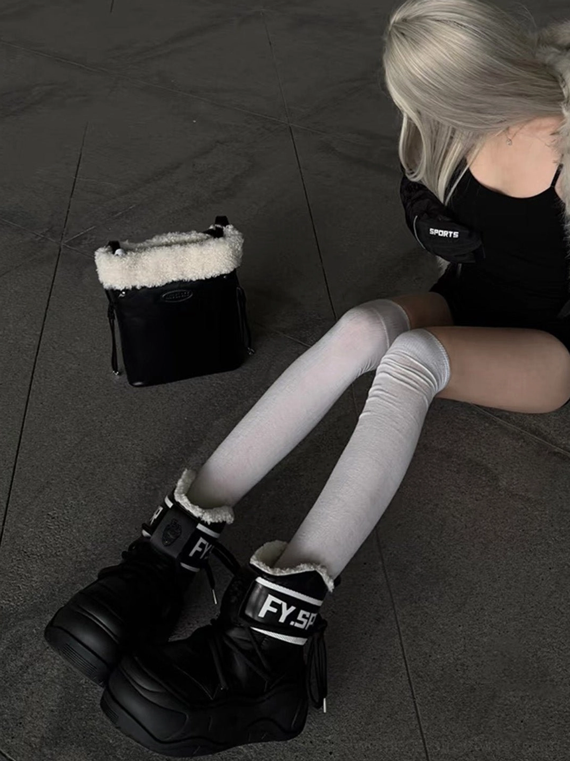 Seated model wearing black faux fur platform moon boots showing side and back ankle details