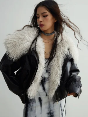 Front three-quarter view of a black faux leather jacket with a detachable oversized off-white faux fur collar and cropped oversized streetwear fit