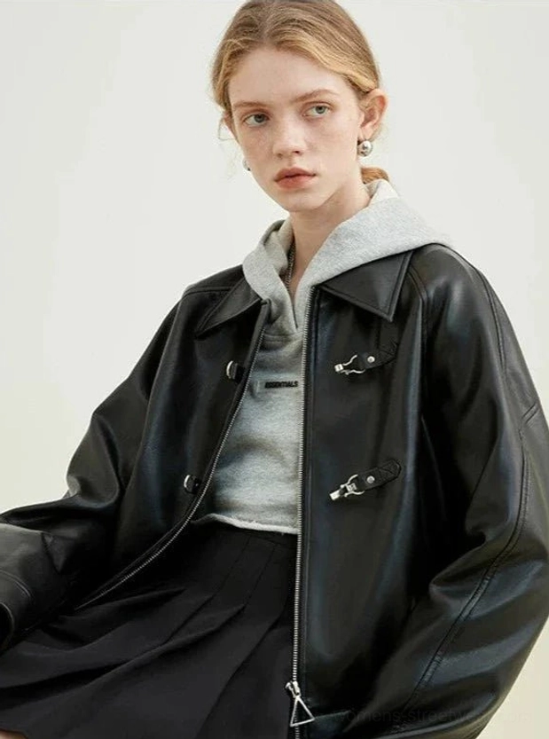 Blonde model wearing black faux leather toggle zip cropped streetwear jacket in a front half-body studio view