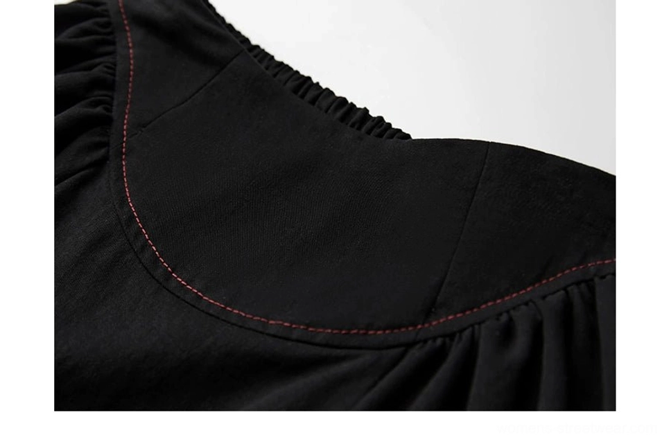 Close-up of curved upper seam with red contrast topstitching on black faux two-piece maxi skirt