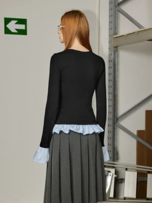 Black faux two-piece ruffle long sleeve streetwear top shown from the back with blue contrast hem and gray pleated midi skirt styling